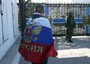 Un uomo con la bandiera russa davanti al quartier generale della flotta ucraina a Sebastopoli